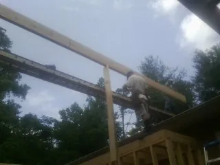 Carpenter setting a ridge beam over a new addition frame — Ice Dam Removal by Roofing Brothers in Surfside