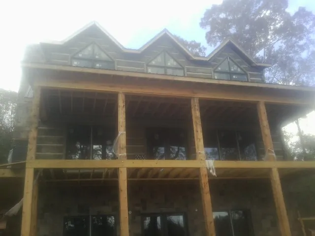 Dormers and porch framing on a large log home under construction — Roof Coating work by our crew in Surfside