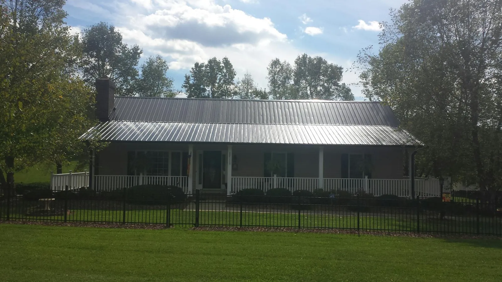 Gray metal roof on a brick ranch with a full width front porch — Gutter Guard Installation work by our crew in Surfside