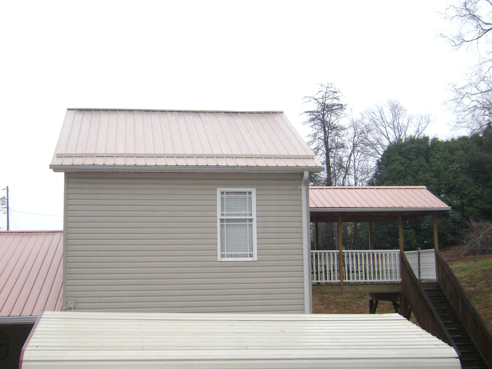 Tan metal roofs on a two story addition and attached porch, from a Roof Replacement job in Surfside